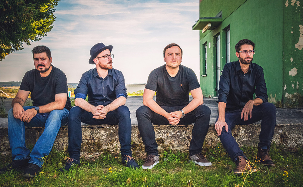 Die Rockband LIO aus Kaiserslautern sitzt entspannt im Sonnenschein auf einer Mauer.